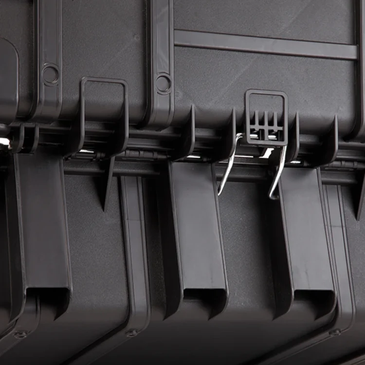 Zbliżenie na dolną część walizki narzędziowej pokazujące szczegóły czarnych zaczepów i elementów mocujących.