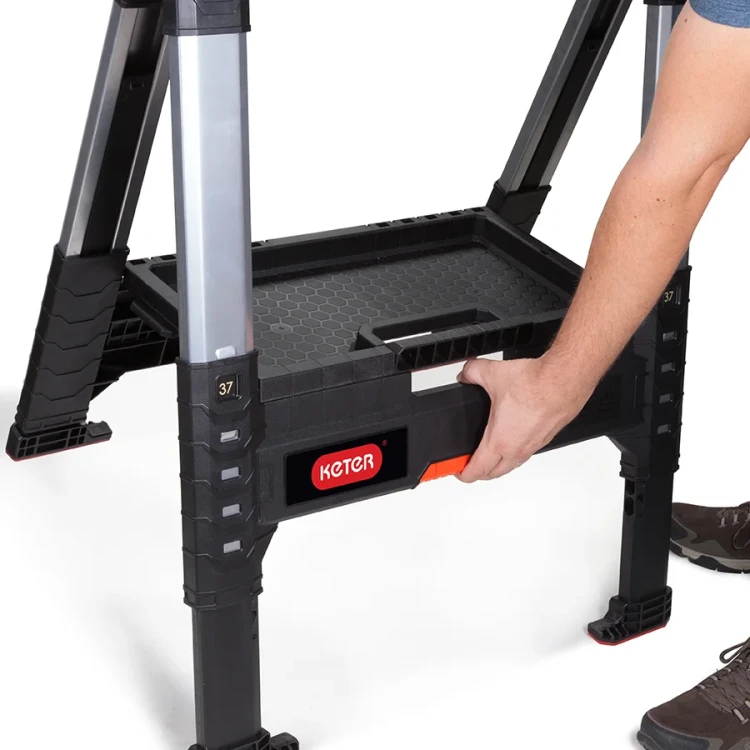 Widok z boku na stojak z wysuniętą półką w środkowej części; dłoń chwyta za uchwyt półki, widoczne nogi osoby.