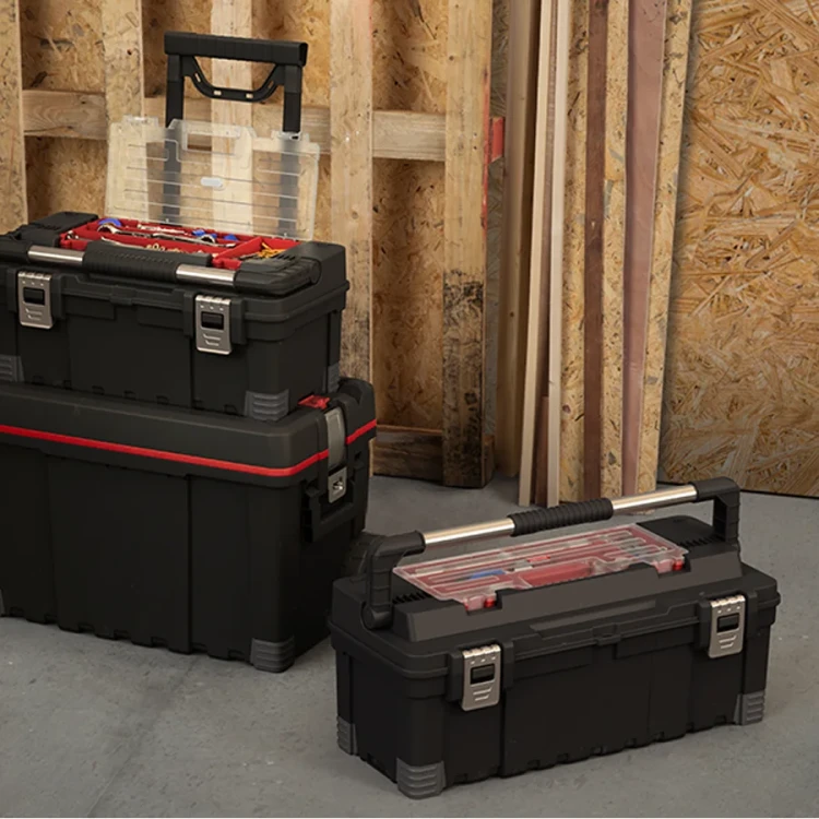 Dwie czarne skrzynki warsztatowe z metalowymi uchwytami i czerwonymi detalami ustawione pionowo przy ścianie z płyt OSB; jedna otwarta z widocznym organizerem.