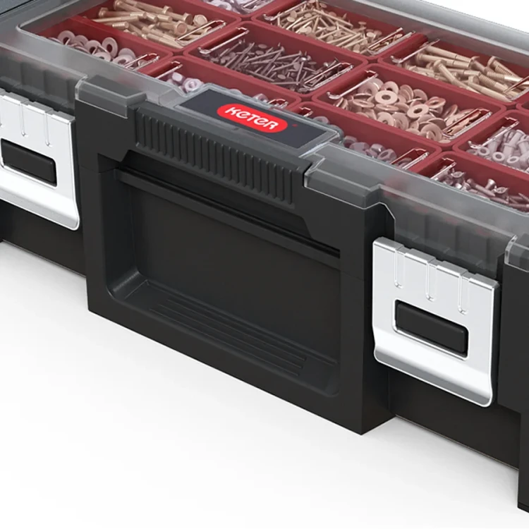 Zbliżenie na front skrzynki narzędziowej z widocznym logo, czarnym uchwytem i metalowymi zapięciami; przez przezroczystą pokrywę widać czerwone przegródki z zawartością.