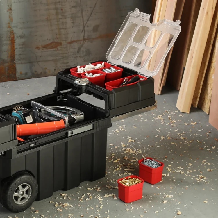 Zbliżenie na rozłożoną część skrzynki z przezroczystą pokrywą i czerwonymi pojemnikami wypełnionymi śrubami i kołkami; dwa pojemniki ustawione obok skrzynki.