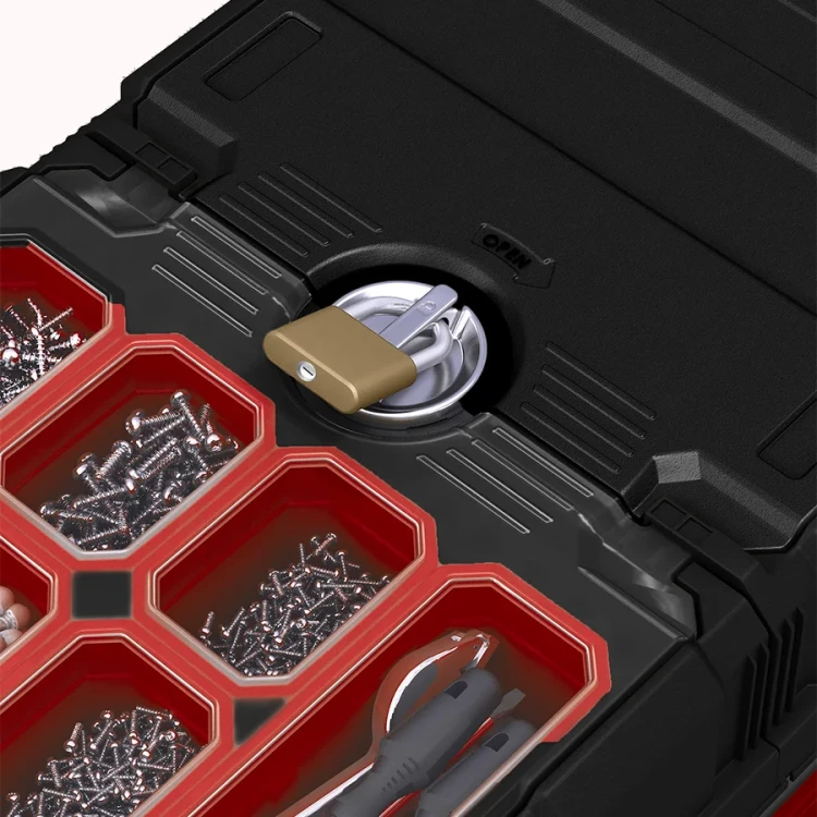 Zbliżenie na pokrywę skrzynki z metalowym zamkiem i kłódką, otaczające go czerwone przegrody wypełnione wkrętami i narzędziami.