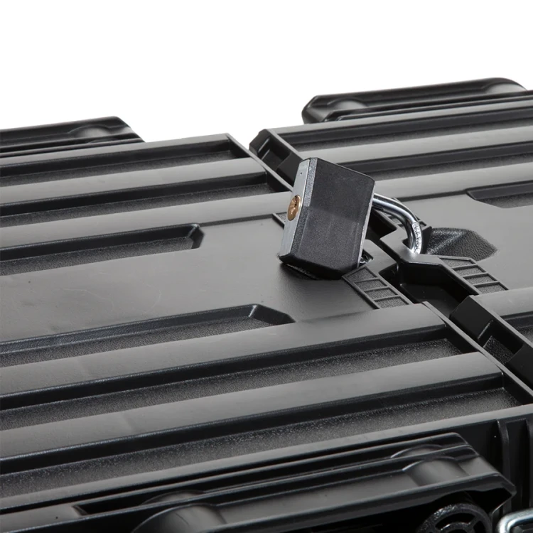 Zbliżenie na górę zamkniętej skrzynki z założoną kłódką w otworze zabezpieczającym; powierzchnia pokrywy z wyraźnymi wzmocnieniami.