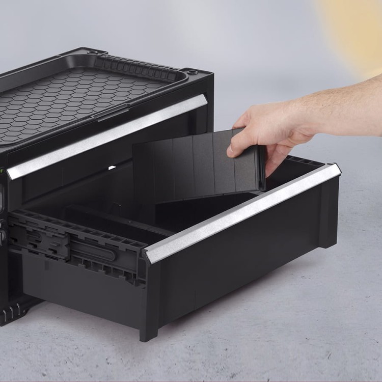 Zbliżenie na czarną szufladę z wyjmowaną przegrodą, na pokrywie widoczny sześciokątny wzór.